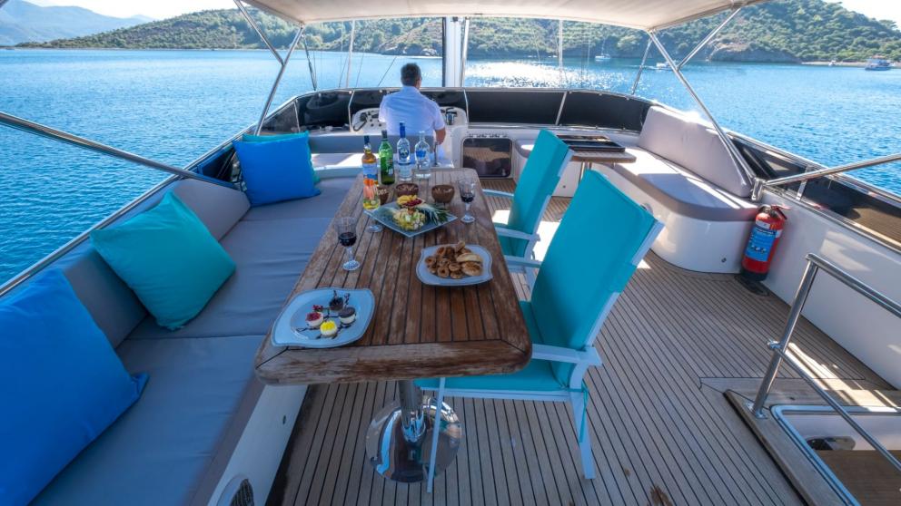 Set table with food and drinks on the deck of a gulet overlooking the sea.