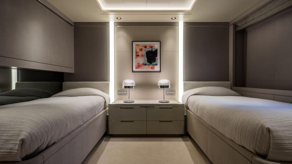 Twin guest bedroom on the Opari yacht with two single beds, stylish lighting, and sea views.