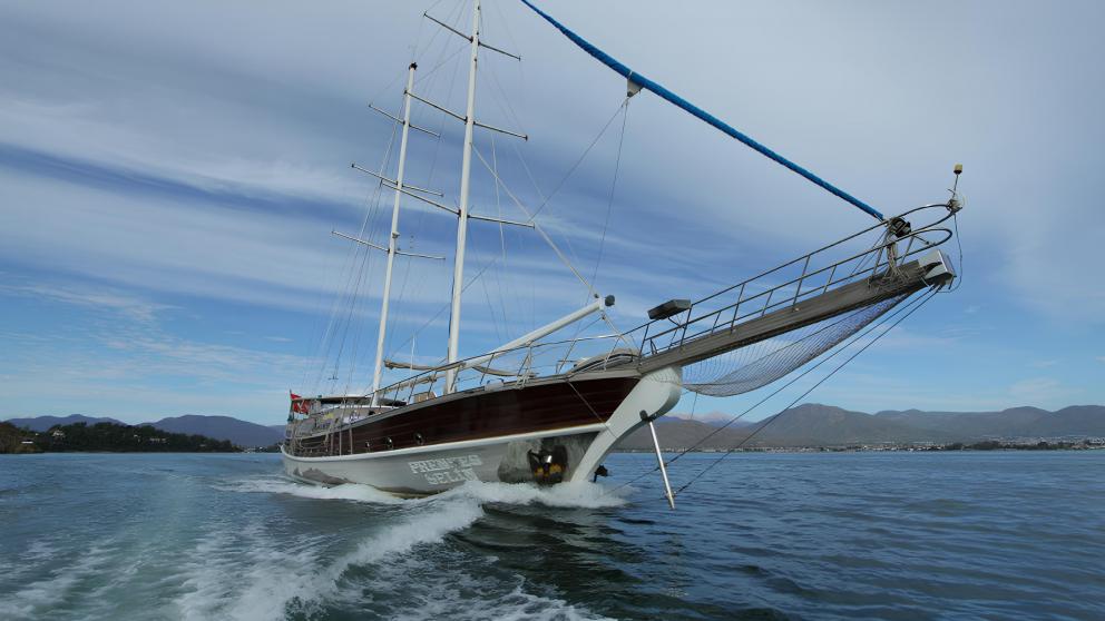 The gulet Prenses Selin sails dynamically through the water in front of a mountain landscape.