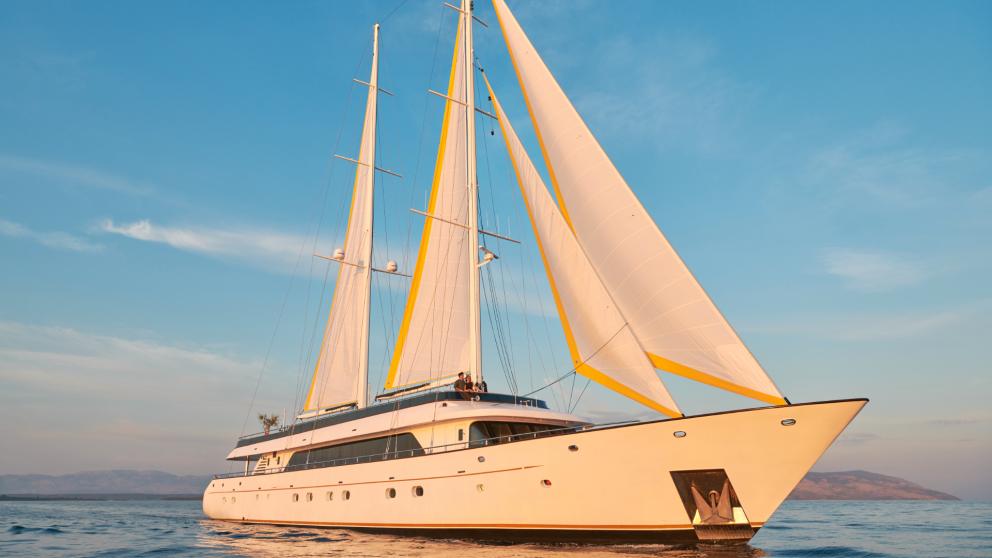 Elegant motor sailor Anima Maris with white sails off the coast of Split at sunset.