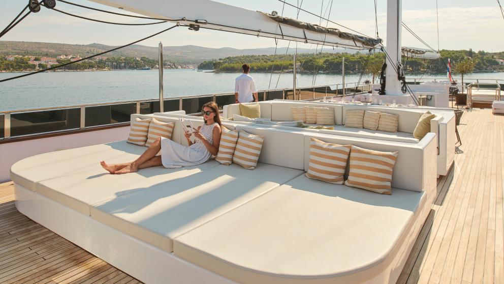 Woman relaxing on the sunny deck of Anima Maris in Croatia, surrounded by comfortable pillows.