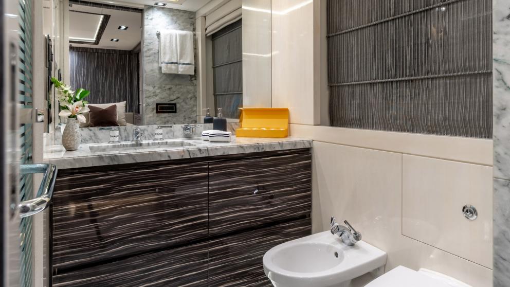 Modern bathroom on a yacht with marble details, elegant washbasin, large mirror and bidet.