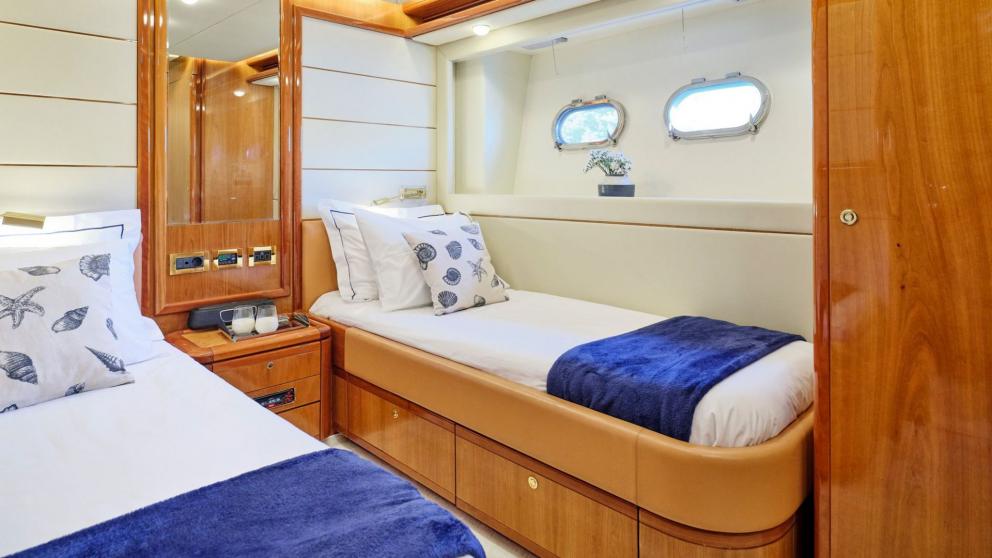Elegant bedroom on a yacht with twin beds, stylish decor, and porthole windows