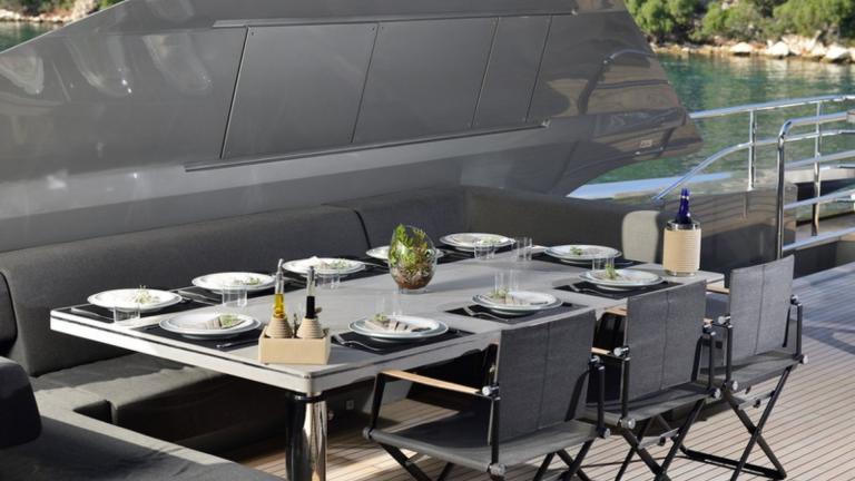 A dining table where you will want to dine and spend time with the open air sea view of a charter yacht.