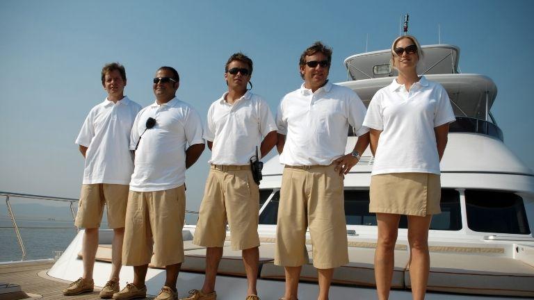 Die 5-köpfige Besatzung in weißen Uniformen wartet auf der Yacht, bereit für die Reise.