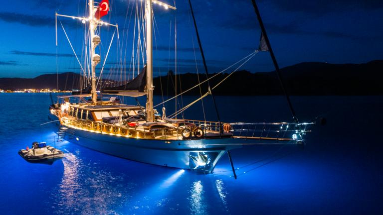 Illumination of the S/Y Voyage gulet at sea. You can see the turquoise water and the dinghy nearby