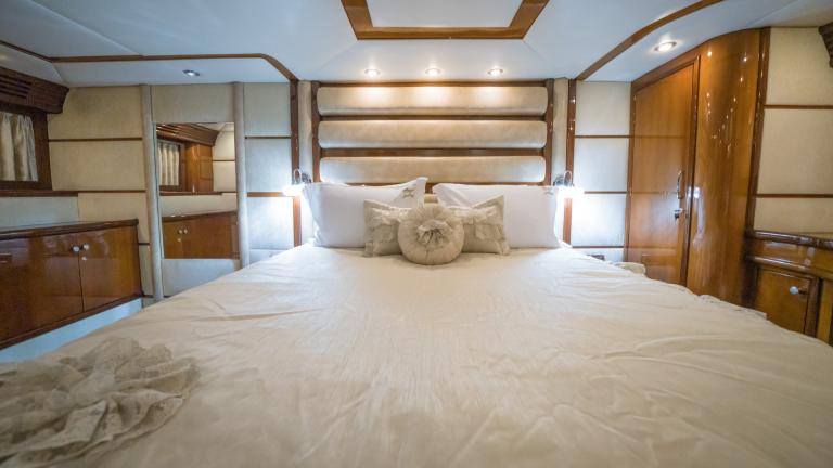 Luxuriously furnished bedroom in quality wood and leather with comfortable bed, mirror and sideboard.