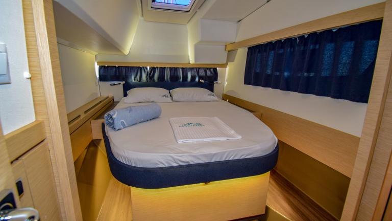 Double bed with bed linen in the cabin. With windows on the walls and ceiling porthole