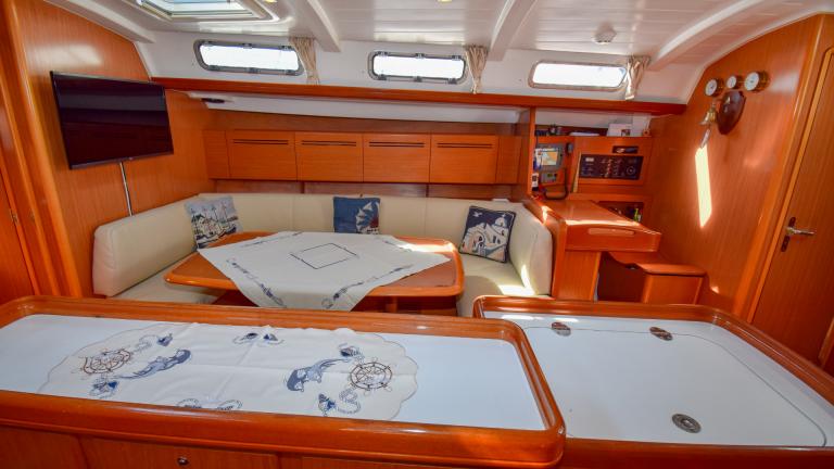 The cabin on the boat has a large TV and a cushioned sofa