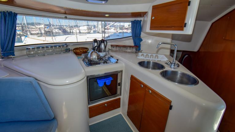 Equipped kitchen with a large window on the catamaran. Gas stove and oven, two sinks and kettles can be seen
