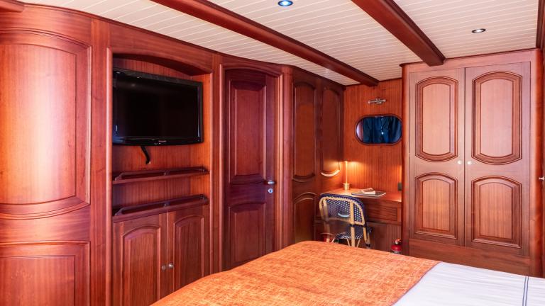 Large S/Y Voyage gulet bedroom for 2 people. You can see the table and TV