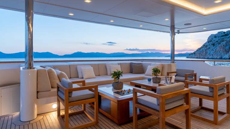 Luxurious lounge on the yacht with comfortable seating and sea views at sunset.