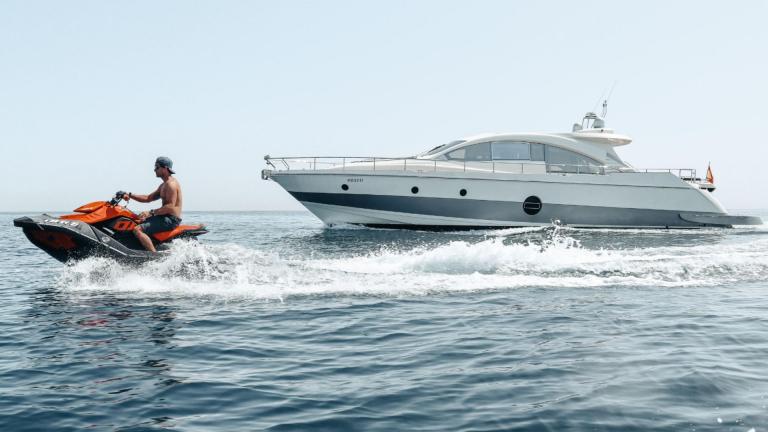 A person rides a jet ski beside motor yacht Manzanos 2 on the sea.