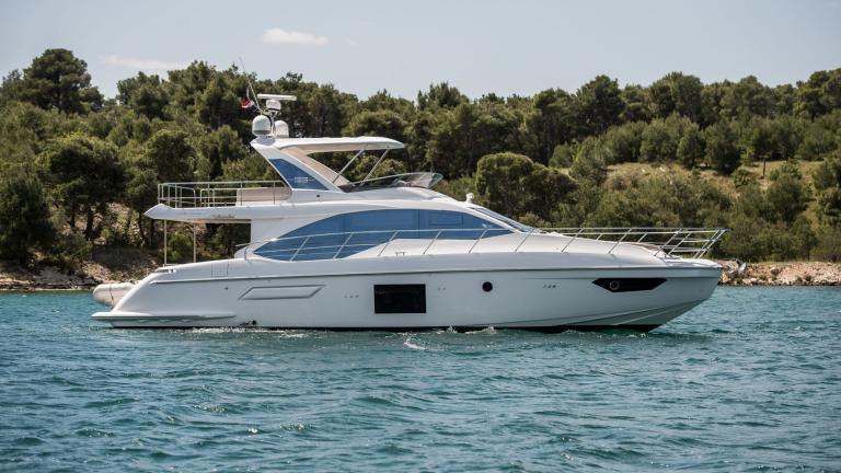 Die moderne Yacht Mawi gleitet vor grüner Küste dahin. Perfekt für Sommercharter.