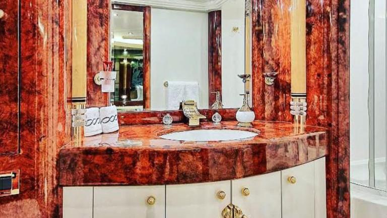 The washbasin area is regally furnished with a pompous cabinet, large mirror and noble decoration.