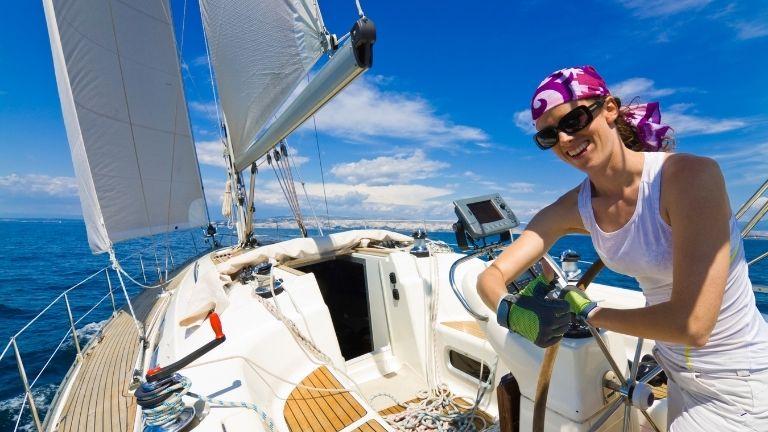 Женщина в солнечных очках плывет на роскошной яхте и позирует.