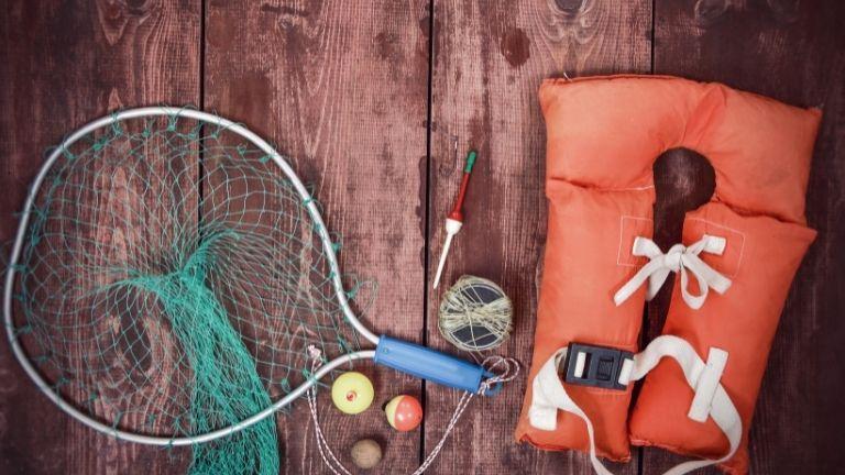 Sea fishing gear laid out, including a life jacket, fishing net, and essential tools