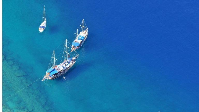 Three boats of different sizes are travelling together in the blue.