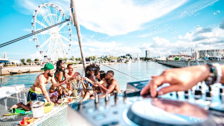 Friends enjoying a yacht party in Bodrum, with drinks, music, and a Ferris wheel in the background—perfect for a summer yacht rental in Turkey