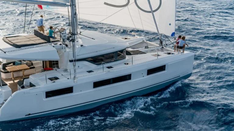 Catamaran Alchera underway, a child at the helm and other guests enjoying the cruise.