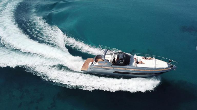 Die Motoryacht Este gleitet rasant über das klare Wasser von Mykonos, während Gäste an Deck entspannen.