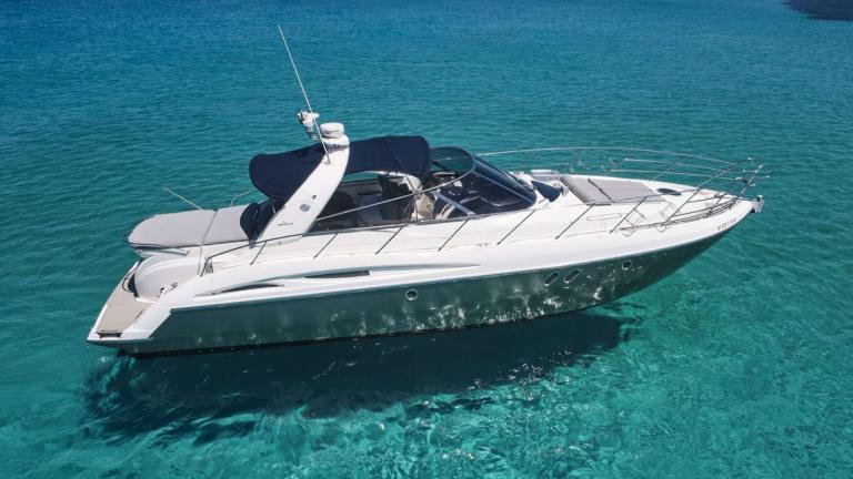Die Motoryacht Com Tu liegt im klaren Wasser vor der Küste von Ibiza.