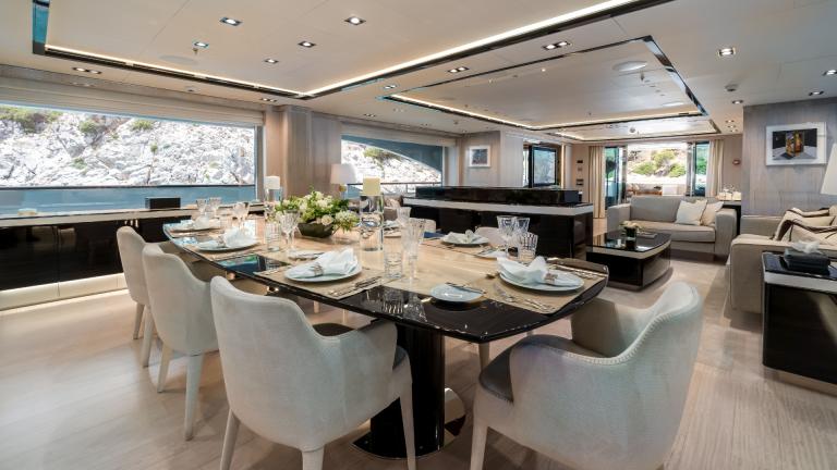 Luxurious dining room on the yacht with table setting, stylish furniture and large windows overlooking the coast.