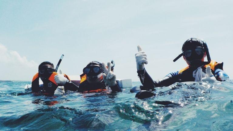 Drei Leute in ihrer Ausrüstung springen von der Yacht und tauchen ab.