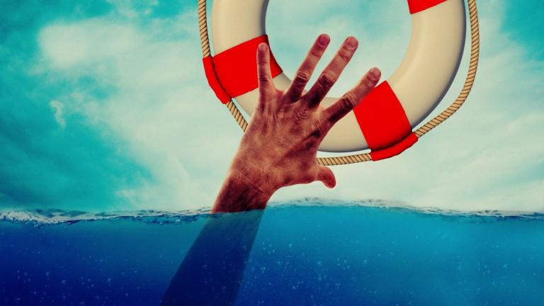 Mann im Wasser greift verzweifelt nach Rettungsschwimmerring um sich zu retten