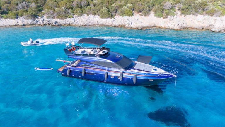 Karan motor yacht anchored in clear turquoise water with a green landscape in the background.