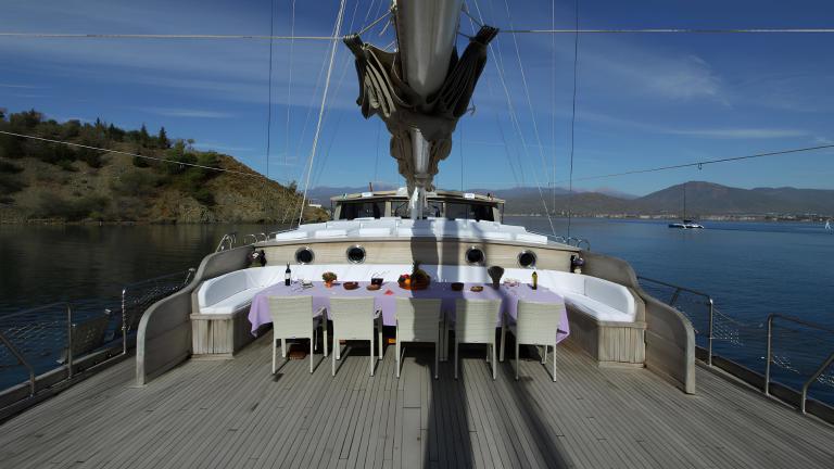 The deck of the gulet Prenses Selin features a stylishly laid dining table with a view of the sea.