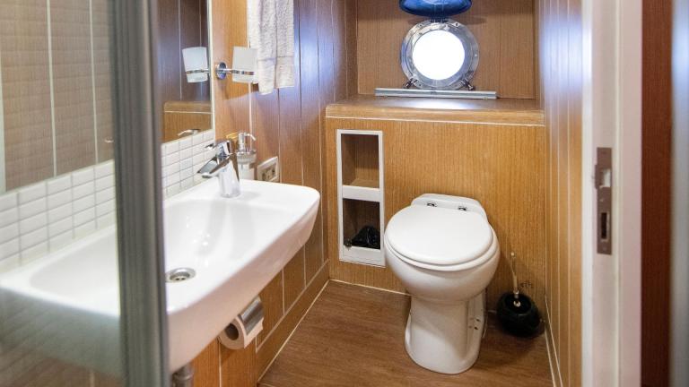 Stylish bathroom with modern fittings, wood panelling and a porthole for natural lighting.