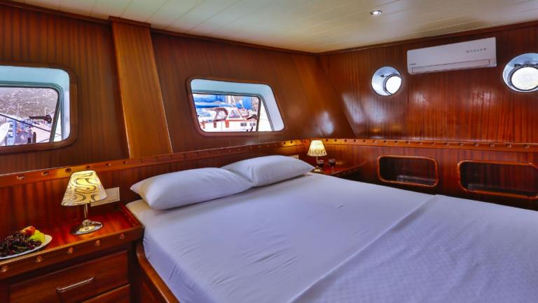 Cabin of the Gulet Victoria with large bed, bedside tables and wooden furnishings.