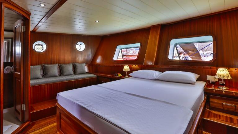 Cabin of the Gulet Victoria with large bed, seating area and wooden furnishings.