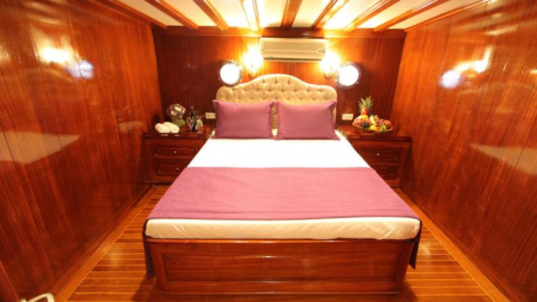 A luxurious bedroom on the gulet Prenses Selin with a large bed and purple bed linen.