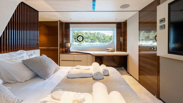 Cozy bedroom with large window and workspace on a yacht.
