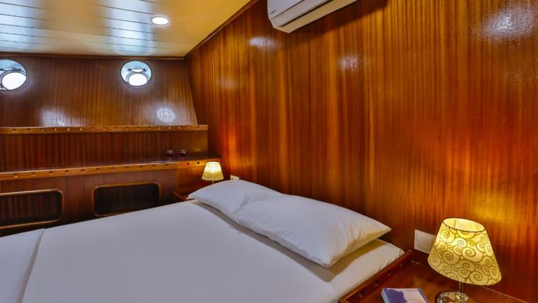Cabin of the Gulet Victoria with large bed, bedside tables and wooden furnishings.