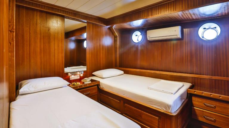 Cabin of the Gulet Victoria with two single beds and wooden furnishings.