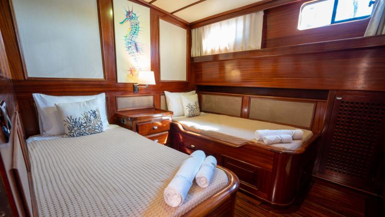 A cosy double cabin on the Gulet Elianora with fine wooden walls, two single beds, stylish decoration and natural light.