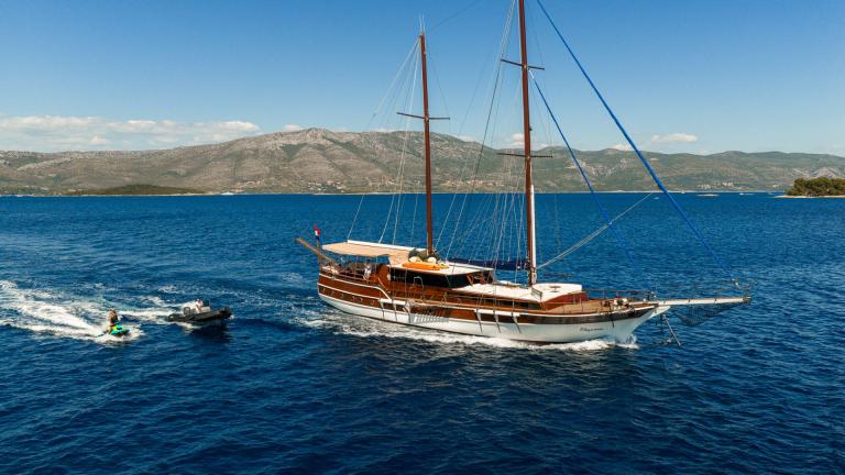 Die Gulet Eleganza segelt durch das blaue Meer bei Split mit Beiboot und Jetski im Schlepptau.