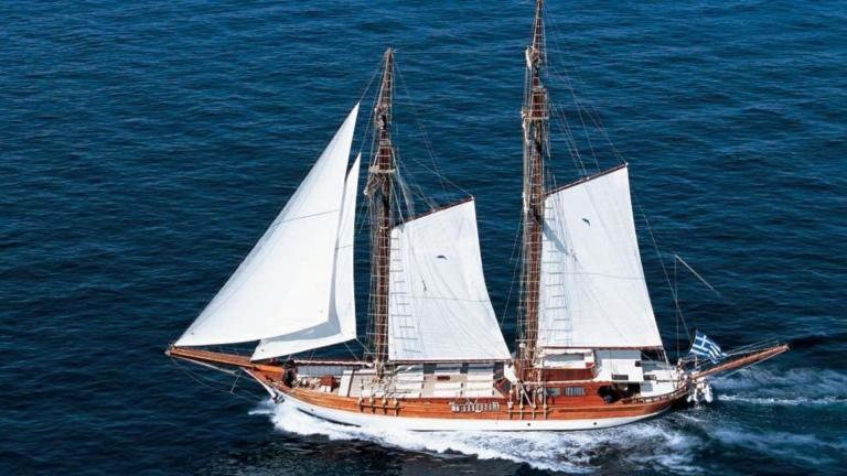 The gulet Matina sails majestically across the open sea in Greece with a Greek flag on the bow.