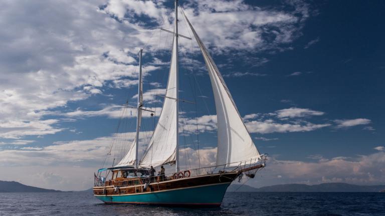 Gulet Valerie sailing in the blue sea, slightly cloudy sky.