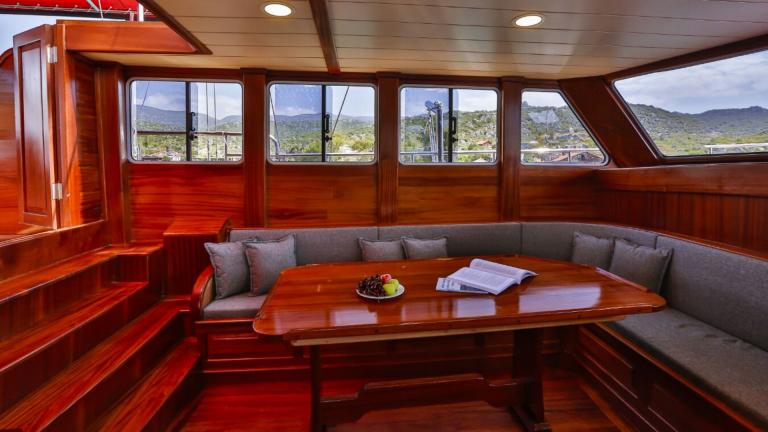 The interior of the Gulet Victoria with an elegant wooden table and cosy seating.