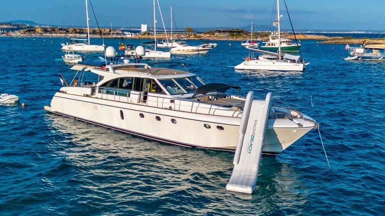 Parodia motor yacht is anchored in a busy bay of Mallorca with a water slide attached.