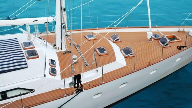 Eine lange Luxusyacht segelt mit geöffneten Fenstern auf dem Deck durch das Meer.