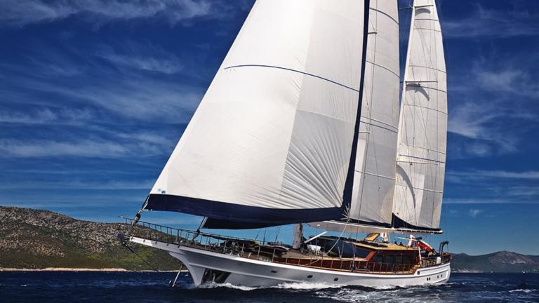 Guleta with her sails up in the blue sea. You can see the mountains