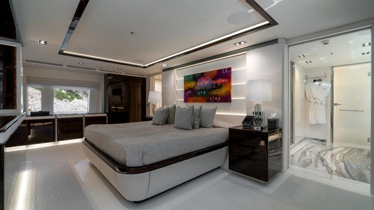 Elegant bedroom on a yacht with large bed, stylish lamps, modern art and direct access to the bathroom.