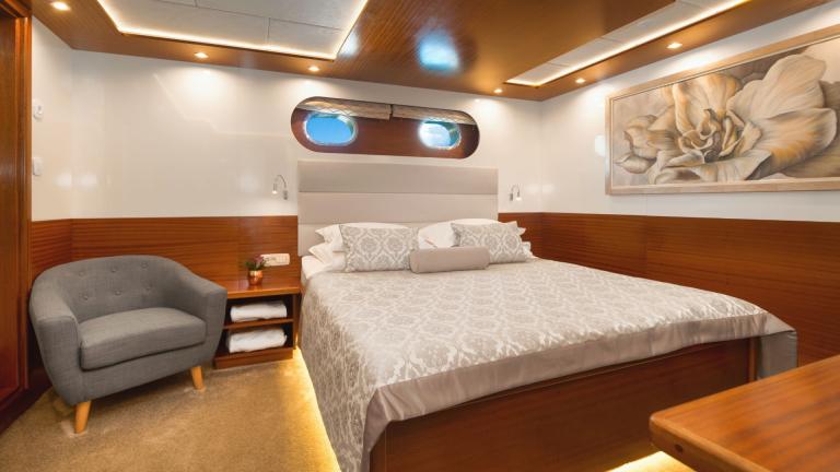 The master cabin is furnished with a double bed, armchair and a painting on the wall.
