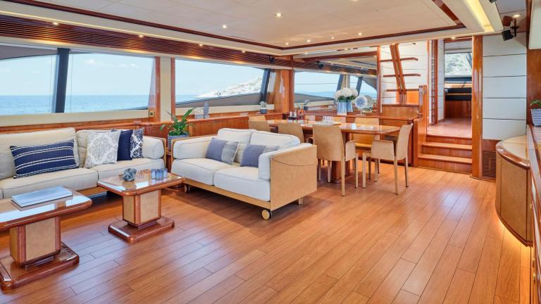Luxurious dining and seating area inside a yacht with sea view through large windows