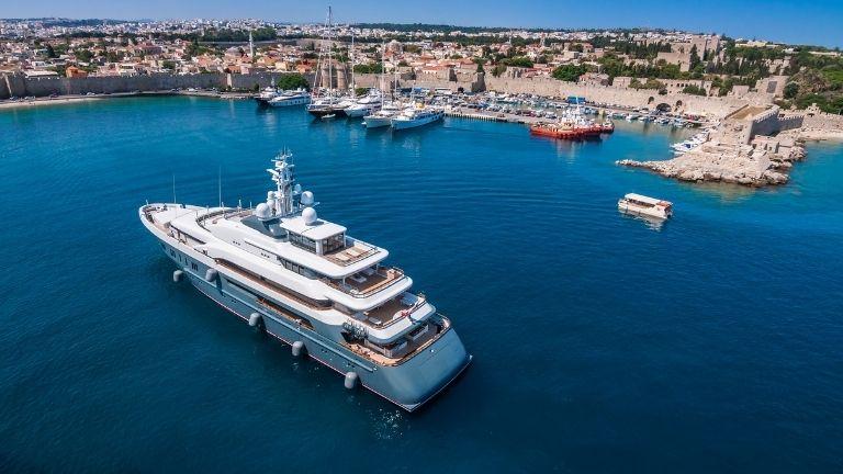 A large and white yacht is sailing on the sea to dock at the port like other yachts.